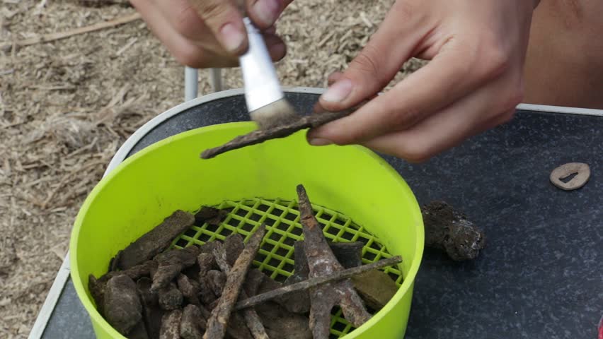 Archaeologist clears rusty tip of medieval spear