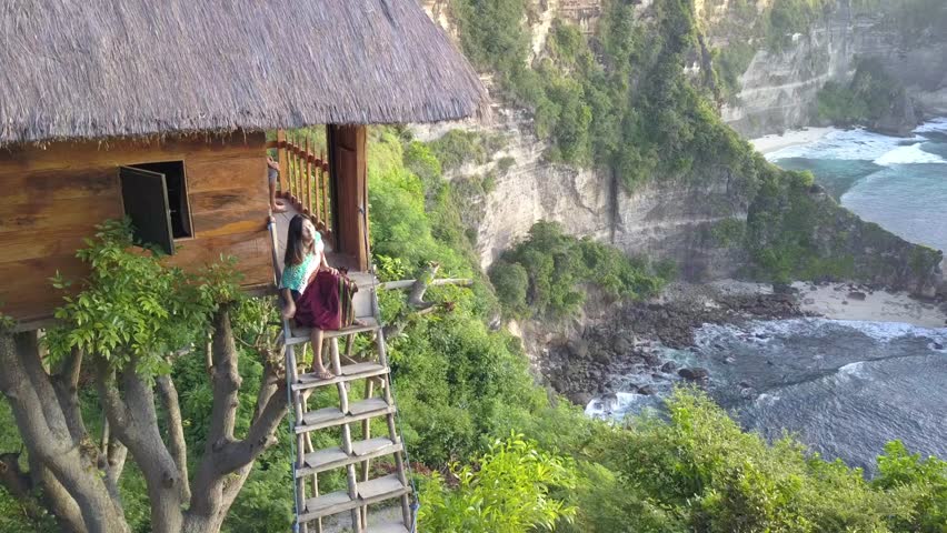 Tourist sitting at the stairs of Tree House (Rumah Pohon) , at Atuh Beach, Nusa Penida, Bali, Indonesia