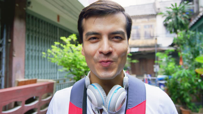 Portrait of asian man blowing bubblegum sweet at camera on Bangkok Asian street. Slow Motion.
