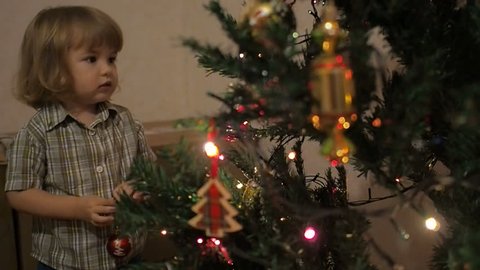 Happy  kid decorate Christmas tree. Little boy decorating christmas tree with toys and balls.