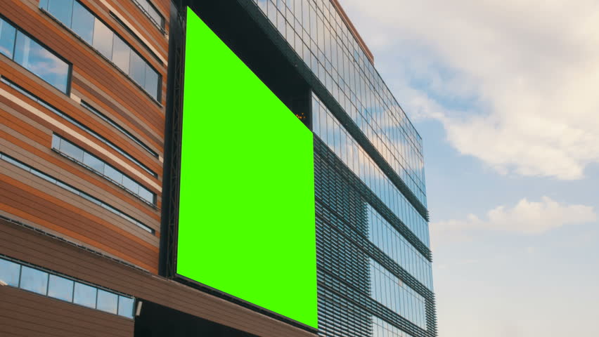 Green screen billboard or large display on shopping mall building in city center. Entertaiment, consumerism and chroma concept. Timelapse shot with moving clouds Royalty-Free Stock Footage #1014615995