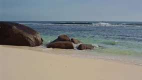 The ocean washes large stones on the shore of Seychelles