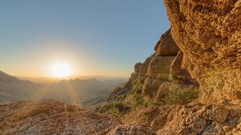 Timelapse of a desert sunrise viewed from a mountain pass.  Shot in HDR.  Includes hyperlapse sliding motion past rocks in the foreground.