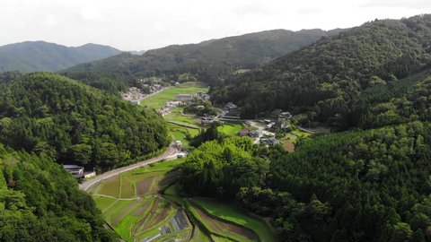 Rice fields in valley surrounded by forested mountains in rural Japan