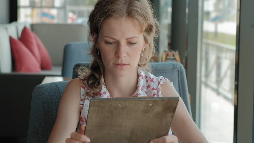Woman is looking through the menu at the restaurant 4k
