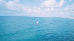 Flight over a fishing trawler and sail boat on blue seas and under blue Skys - B Roll