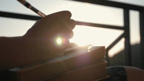 Woman's hand close-up, writing a note or letter to a notebook with a pen on a sunny day at sunset. A stack of scientific books, preparation for exams. Filling out the report - Powered by Shutterstock - Get 15% off with code: PIKWIZARD15