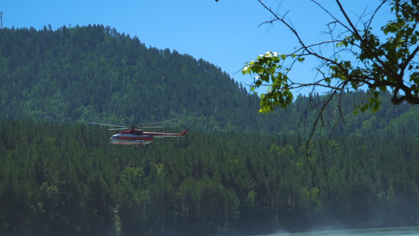 The helicopter Mil Mi-8, which protects the forest from fires, takes off from the shore of a mountain river.