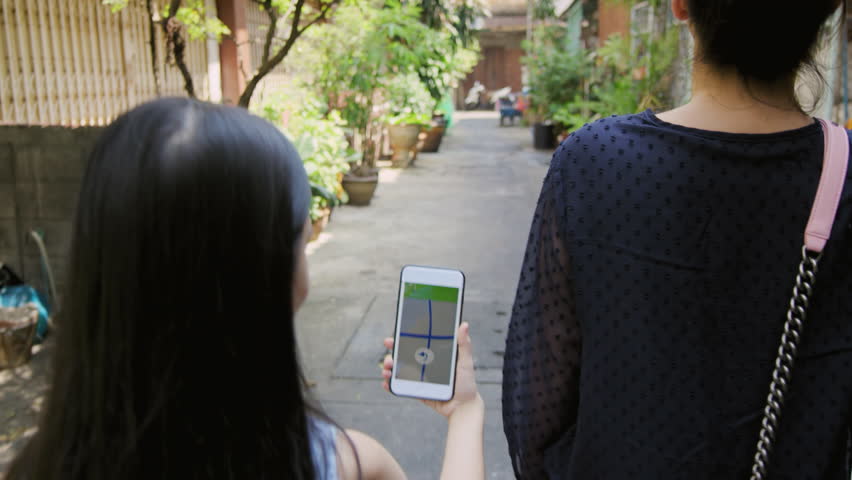 Asian mother and daughter walking together looking for an address with a gps navigator on a smartphone in Bangkok city alley way street inThailand Asia. Slow motion.