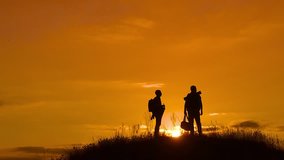 two men tourists lifestyle hikers silhouette go to the mountains sunset travel slow motion video. Traveler successful young men walking on top of Mountain and waiting for sunrise. travel tourists in