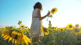 Happy little girl runs happy free across the field with sunflowers. slow motion video. smelling big sunflower on summer field. Delight of a pleasant smell. Summer holiday. concept happiness childhood
