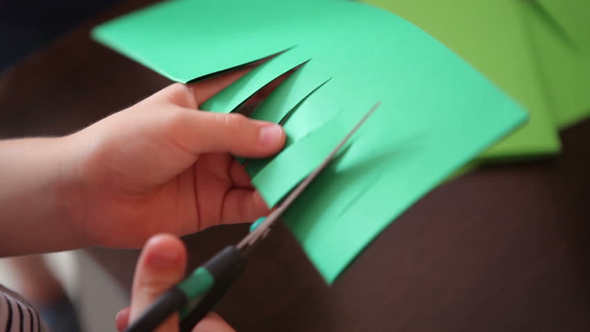 The child cuts green paper with scissors. Children at a table made of green paper make an applique Royalty-Free Stock Footage #1014654029