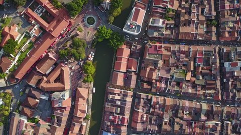 Top down aerial view of buildings, street, and market along a river in Melaka, Malaysia