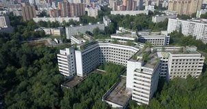 4K aerial video of dilapidated abandoned unfinished fenced off Moscow hospital with strange triangle structure shape and Grachevka estate park area around on summer morning in Russian capital