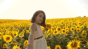 Dad and daughter walking along the field with sunflowers at sunset holding hands First-person view. Slow motion video. follow me. little girl and boy teenager run by the hand over the field with