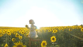 Happy little girl running happy free across the field with sunflowers. slow motion video . smelling big sunflower on summer field. Delight of a pleasant smell. Summer lifestyle holiday . concept