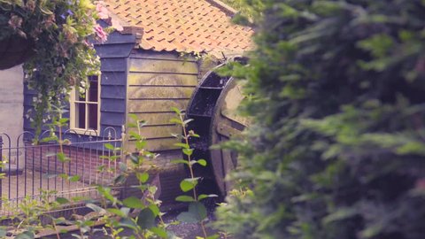 4K dolly shot of water wheel with plants in foreground.