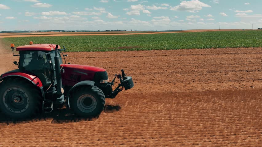 Aerial drone view of red tractor working in wheat field. Agriculture and environment in European Union. Royalty-Free Stock Footage #1014670139
