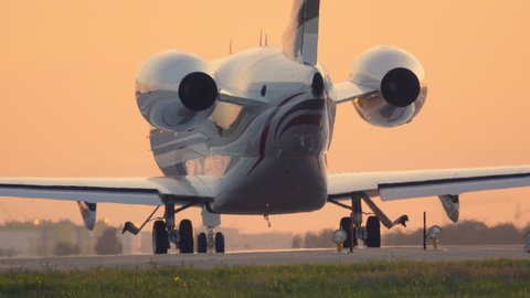 Business jet on a runway before taking off at sunset. Back view