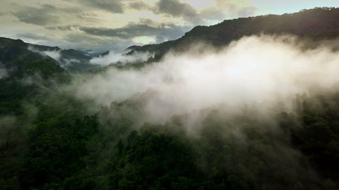 Aerial view of a village in the lush green rain cloud cover tropical rain forest mountain during the rainy season in the northern Thailand
