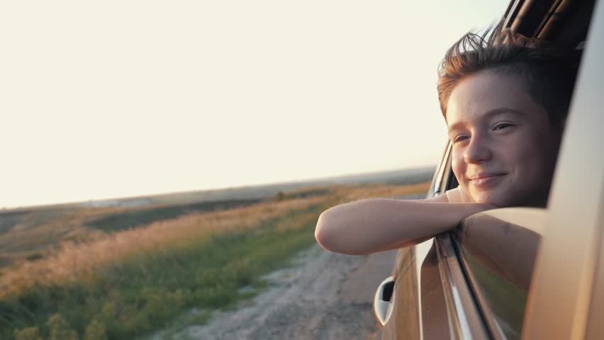 Teen boy looking out car window. Summer trip with family. Boy is dream. Happy boy traveling with family. Dream kid. Happy family traveling by car. Smile of kid in car window Royalty-Free Stock Footage #1014677951