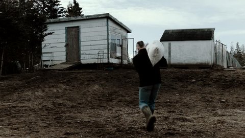 Canning, Nova Scotia / Canada - MAR 15 2018: farmer carrying a bag of grain to feed the poultry in the morning
