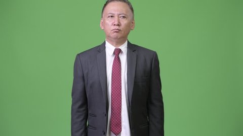 Mature Japanese businessman farting against green background