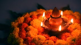 Footage of glowing clay lamp of Diwali Festival decorated with marigold flowers, rotating