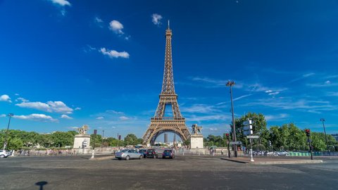 Eiffel Tower with traffic on a bridge over Siene river in Paris timelapse hyperlapse, France. Blue cloudy sky at summer day with green trees and people walking around
