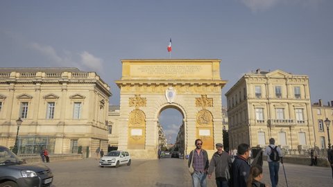 Montpellier, France - April, 2017: People walking and driving near the Triumphal Arch of Montpellier.