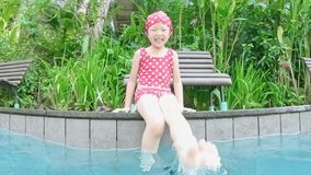 cute girl kicking water happily in the swimming pool