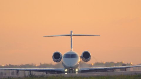 Business jet taxiing on the runway before take off at sunset