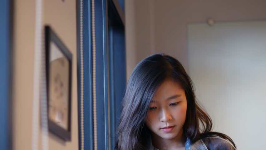 Young asian woman using tablet beside window at office. Royalty-Free Stock Footage #1014724172