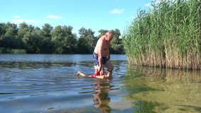 4K Smiling grandfather and grandchild kid around in the river
