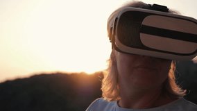 Blonde girl with virtual reality glasses at sunset. Modern technologies. Virtual life and communication