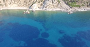Aerial drone video of beach, sea under cliffs and big mountain reveal, forward camera movement