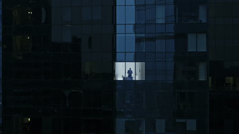 Aerial View Footage: From Outside into Office Building with Businessman Using Mobile Phone and Standing by the Office Window. Shot on RED EPIC-W 8K Helium Cinema Camera.
