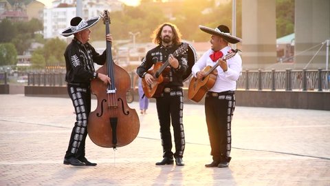 Trio of Mexican musicians mariachi give street concert in the city at sunset. Live camera