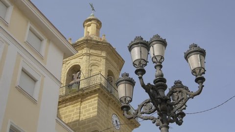 Cadiz, Spain - April, 2017: A lamp post near a bell tower