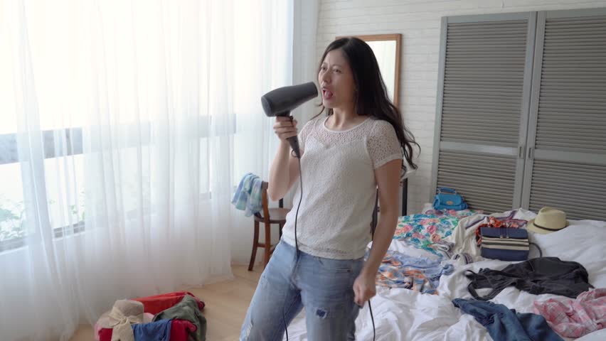 Asian young lady image herself a superstar and sing and dance in her bedroom. She is full of drama cell. Hairdryer is his microphone. Royalty-Free Stock Footage #1014776411