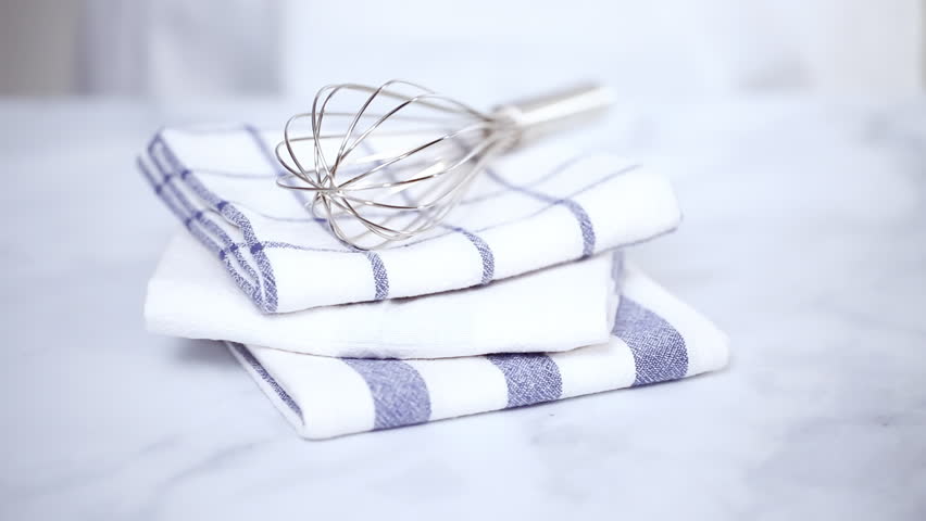 Folding blue and white patterned paper towels on marble surface.