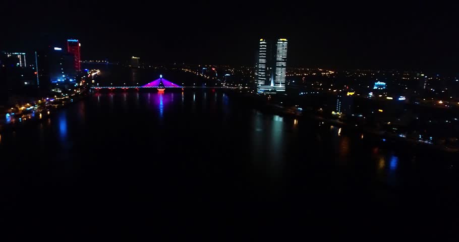 Aerial view of night bridge Da Nang city of beautiful skyscrapers.Big city lights illumination buidings of beach cost asian city of central Vietnam.