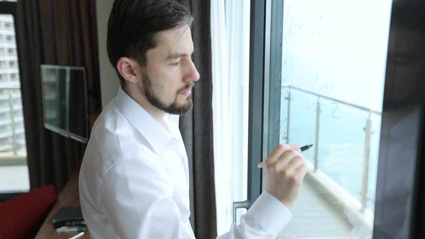 Businessman writes on window glass business plan with economic calculations