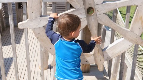 A cute little boy playing on a wooden pirate ship at the playground