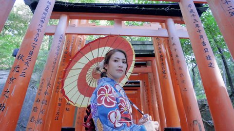 Asian women in traditional japanese kimonos is smiling and happiness at Fushimi Inari Shrine in Kyoto, Japan.