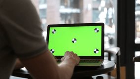 Man Using Laptop Computer With Green Screen In Restaurant