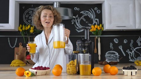 Beautiful Young Woman In Kitchen Squeezing Orange Juice With Juicer