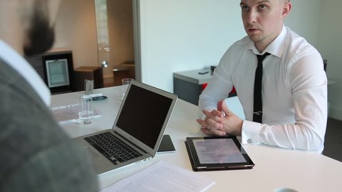 Two men conduct business negotiations in office, sitting at table