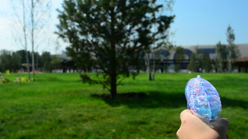 Toy gun shooting bubbles in park close up