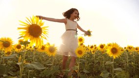 Cute lifestyle child girl in yellow garden sunflowers sunlight in summer. beautiful sunset little girl in sunflowers. slow motion video. girl teenager and sunflowers field concept agriculture